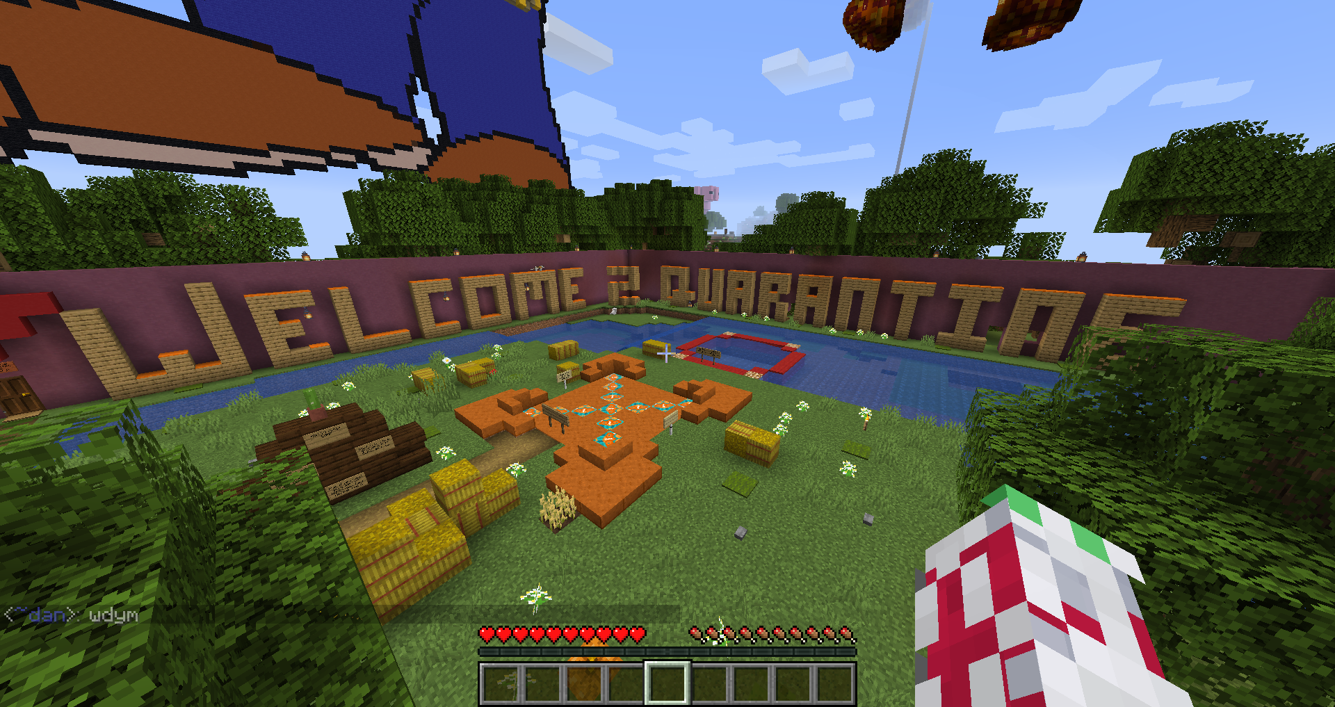 Figure 2 A screenshot of the video game Minecraft. Visible is a peaceful area with small signage for players. In large text against a wall is written “WELCOME 2 QUARANTINE” in wood blocks.